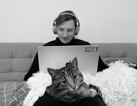 Alex with his cat, working on a laptop